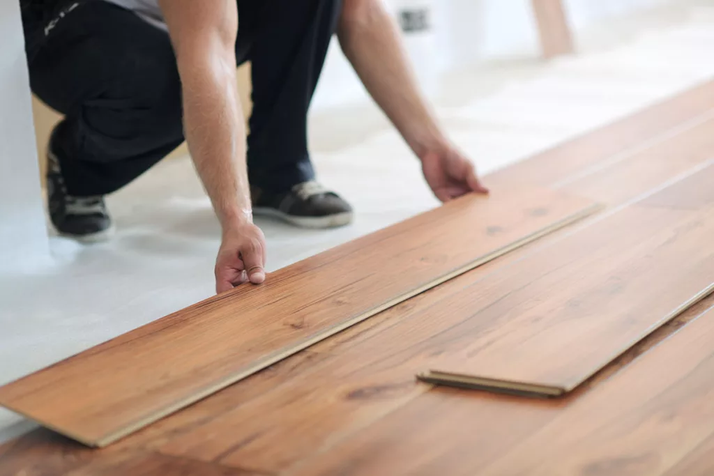 A person installs laminate wood flooring for a commercial remodel.